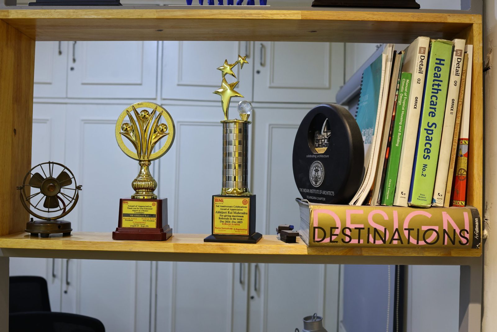 Shelf with industry awards, an Indian Institute of Architects memento and design books