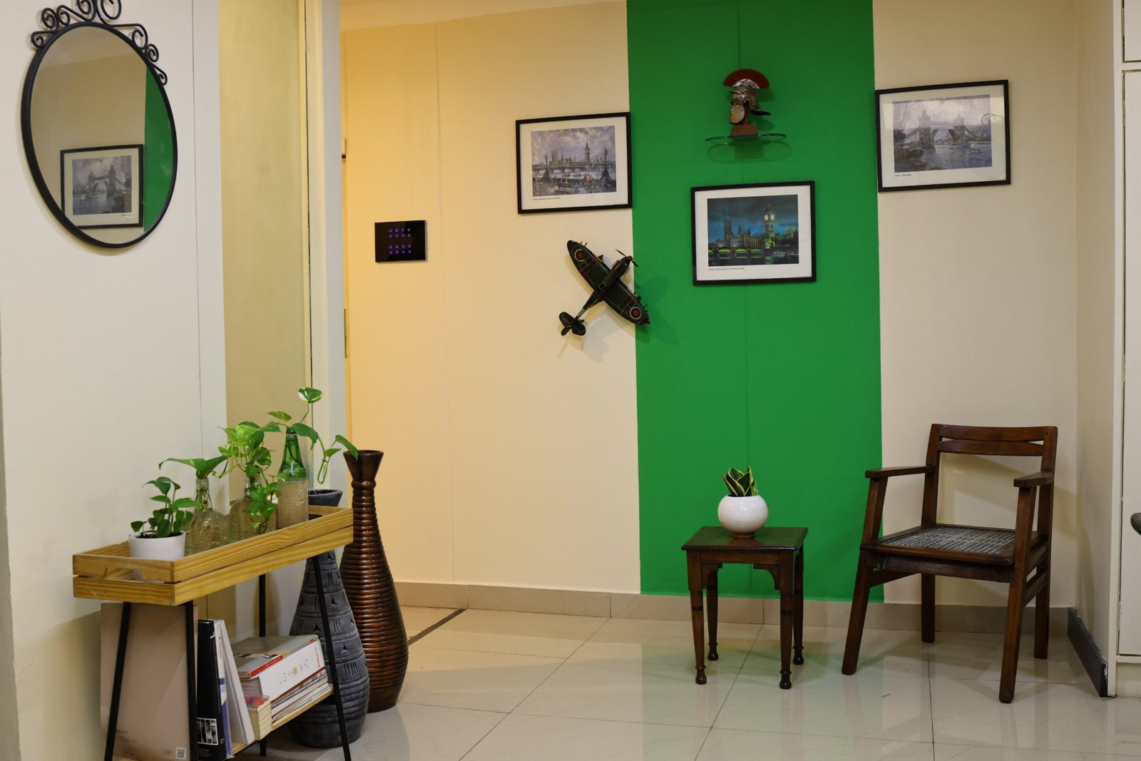 Studio lounge with a green feature wall, framed London prints and a vintage wooden chair