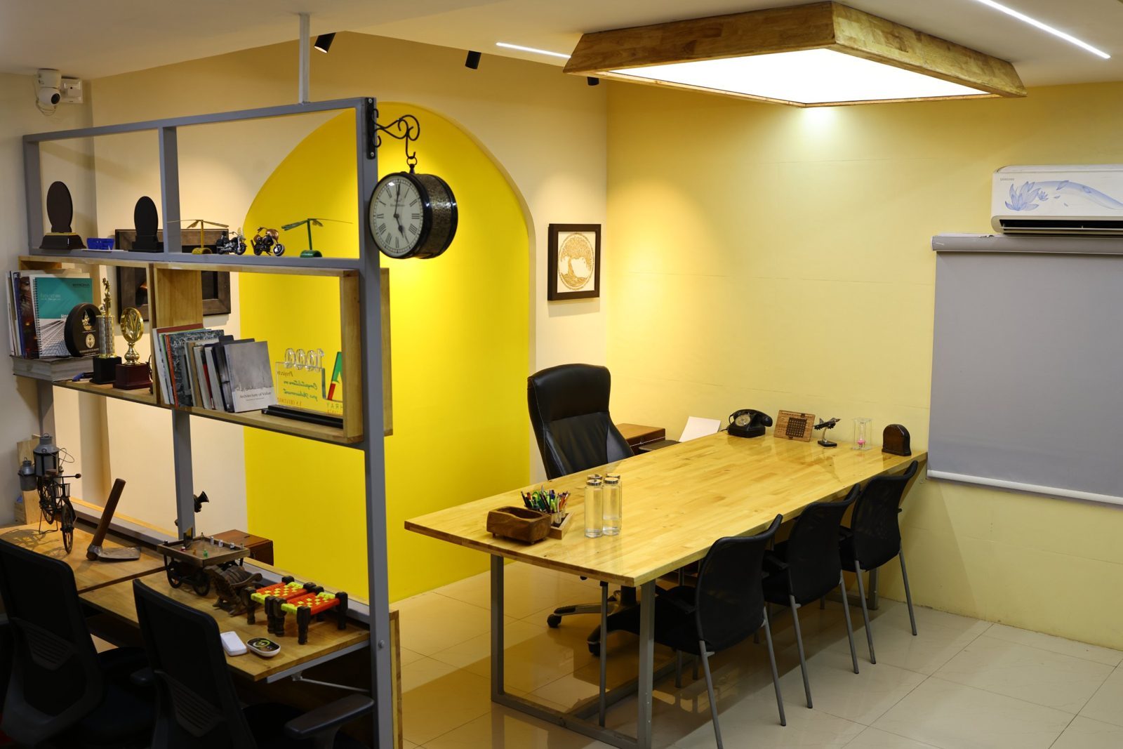 Meeting room with a long timber table, display shelving and a yellow arched niche